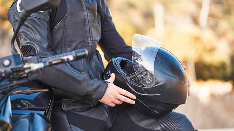 Man sitting on motorcycle holding his helmet.